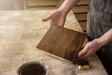 Image showing Carpenter painting wooden