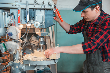 Image showing Carpenters with electric drill machine drilling wooden board