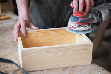 Image showing Worker grinds the wood box