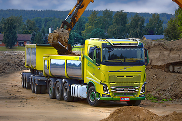 Image showing Excavator Loading Soil onto Green Volvo FH16 Truck Trailer