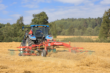 Image showing Farm Tractor and Twin Rotary Rake Working in Field