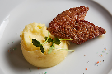 Image showing delicious mashed potatoes sprinkled with greens, juicy meat cutl