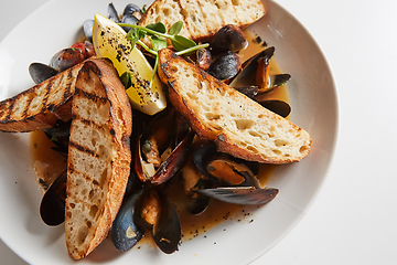 Image showing Seafood. Mussels in wine with croutons and lemon. Clams in the shells.