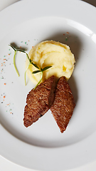 Image showing delicious mashed potatoes sprinkled with greens, juicy meat cutl