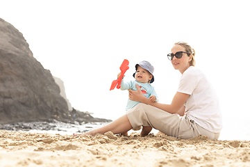 Image showing Mother playing his infant baby boy son on sandy beach enjoying summer vacationson on Lanzarote island, Spain. Family travel and vacations concept.