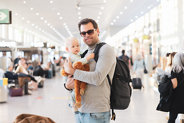 Image showing Father traveling with child, holding his infant baby boy at airport terminal waiting to board a plane. Travel with kids concept.