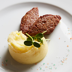 Image showing delicious mashed potatoes sprinkled with greens, juicy meat cutl