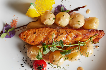 Image showing Roast salmon with potatoes on white plate. Shallow dof