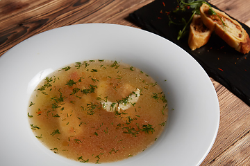 Image showing Beautiful presentation of the fish soup in a white plate, with b