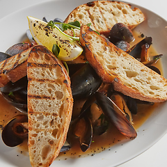 Image showing Seafood. Mussels in wine with croutons and lemon. Clams in the shells.
