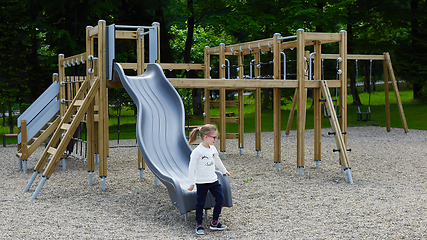 Image showing Little girl on a playground. Child playing outdoors in summer. Kids play on school yard.