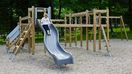 Image showing Little girl on a playground. Child playing outdoors in summer. Kids play on school yard.