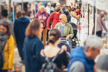 Image showing Mother waling and pushing his infant baby boy child in stroller in crowd of unrecognizable people wisiting sunday flea market in Malaga, Spain.