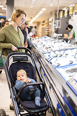 Image showing Casualy dressed mother choosing fish in the fish market department of supermarket grocery store with her infant baby boy child in stroller.