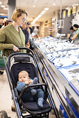 Image showing Casualy dressed mother choosing fish in the fish market department of supermarket grocery store with her infant baby boy child in stroller.