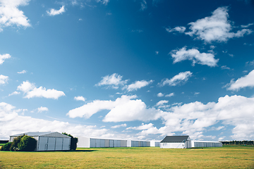 Image showing Steel barn on a farm with cloudy blue sky.