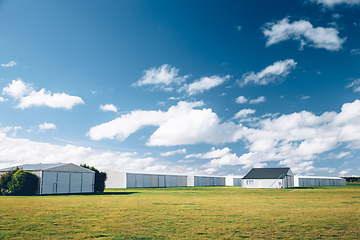 Image showing Steel barn on a farm with cloudy blue sky.