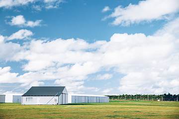 Image showing Steel barn on a farm with cloudy blue sky.