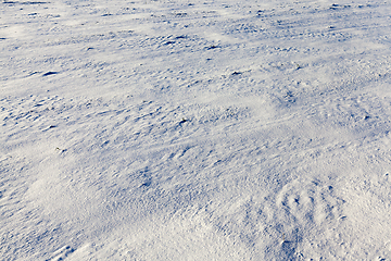 Image showing snow-covered soil surface close up - snow-covered soil surface is not smooth. Photographed close-up.