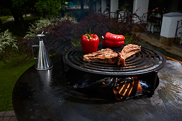 Image showing Tomahawk rib beef steak and T-bone on hot black grill.