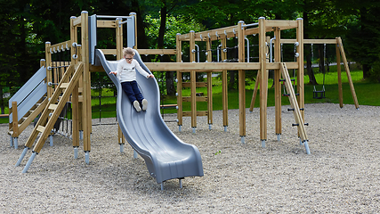 Image showing Little girl on a playground. Child playing outdoors in summer. Kids play on school yard.