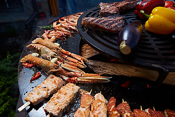 Image showing Tomahawk rib beef steak and T-bone on hot black grill.