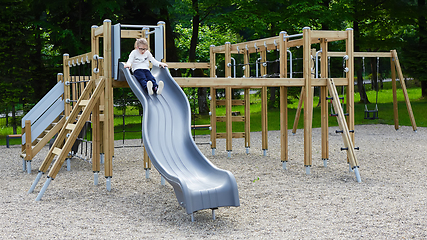 Image showing Little girl on a playground. Child playing outdoors in summer. Kids play on school yard.