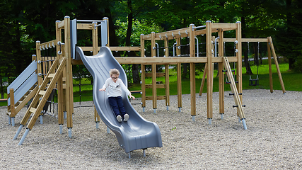 Image showing Little girl on a playground. Child playing outdoors in summer. Kids play on school yard.