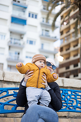 Image showing Young mother with her cute infant baby boy child on bench in city park.