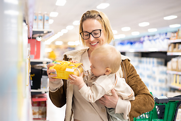 Image showing Caucasian mother shopping with her infant baby boy child choosing products in department of supermarket grocery store.