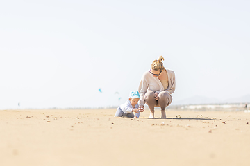 Image showing Mother playing his infant baby boy son on sandy beach enjoying summer vacationson on Lanzarote island, Spain. Family travel and vacations concept.