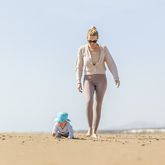 Image showing Mother playing his infant baby boy son on sandy beach enjoying summer vacationson on Lanzarote island, Spain. Family travel and vacations concept.