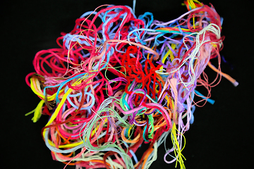 Image showing Ball of multicolored tangled threads for needlework on black bac