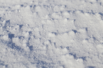 Image showing land covered with snow - white snow after snow had fallen and covered the land in the agricultural field. Photo closeup in the winter season, a small depth of field. On visible surface roughness snow