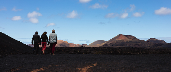 Image showing Tourists visiting volcanic landscape of Timanfaya National Park in Lanzarote. Popular touristic attraction in Lanzarote island, Canary Islands, Spain.