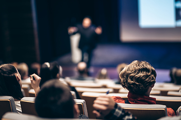 Image showing Speaker giving a talk in conference hall at business event. Rear view of unrecognizable people in audience at the conference hall. Business and entrepreneurship concept.