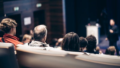 Image showing Speaker giving a talk in conference hall at business event. Rear view of unrecognizable people in audience at the conference hall. Business and entrepreneurship concept.