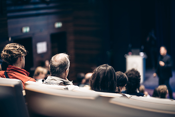 Image showing Speaker giving a talk in conference hall at business event. Rear view of unrecognizable people in audience at the conference hall. Business and entrepreneurship concept.