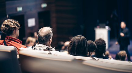 Image showing Speaker giving a talk in conference hall at business event. Rear view of unrecognizable people in audience at the conference hall. Business and entrepreneurship concept.