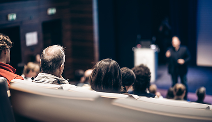 Image showing Speaker giving a talk in conference hall at business event. Rear view of unrecognizable people in audience at the conference hall. Business and entrepreneurship concept.