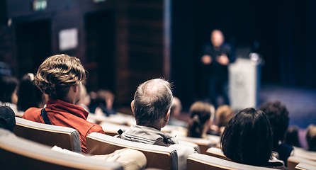 Image showing Speaker giving a talk in conference hall at business event. Rear view of unrecognizable people in audience at the conference hall. Business and entrepreneurship concept.