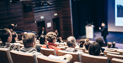 Image showing Speaker giving a talk in conference hall at business event. Rear view of unrecognizable people in audience at the conference hall. Business and entrepreneurship concept.