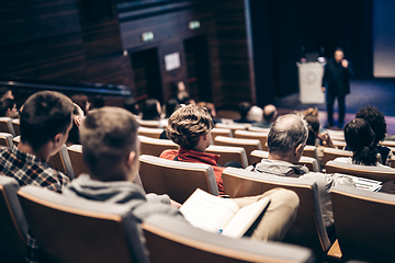 Image showing Speaker giving a talk in conference hall at business event. Rear view of unrecognizable people in audience at the conference hall. Business and entrepreneurship concept.