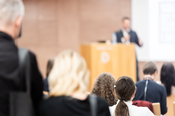 Image showing Speaker giving a talk in conference hall at business event. Rear view of unrecognizable people in audience at the conference hall. Business and entrepreneurship concept.