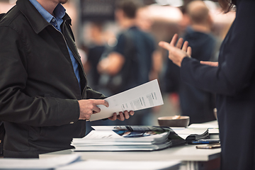 Image showing Business people exchanging business promotional materials and brochure on business meeting on trade-show. Business discussion talking deal concept.