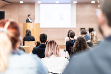 Image showing Speaker giving a talk in conference hall at business event. Rear view of unrecognizable people in audience at the conference hall. Business and entrepreneurship concept.