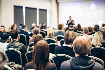 Image showing Speaker giving a talk in conference hall at business event. Rear view of unrecognizable people in audience at the conference hall. Business and entrepreneurship concept.