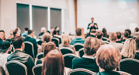 Image showing Speaker giving a talk in conference hall at business event. Rear view of unrecognizable people in audience at the conference hall. Business and entrepreneurship concept.