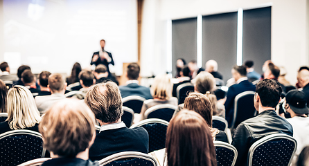 Image showing Speaker giving a talk in conference hall at business event. Rear view of unrecognizable people in audience at the conference hall. Business and entrepreneurship concept.