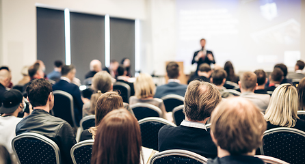 Image showing Speaker giving a talk in conference hall at business event. Rear view of unrecognizable people in audience at the conference hall. Business and entrepreneurship concept.